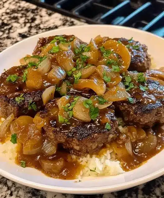 Plated hamburger steak with onion gravy served alongside mashed potatoes