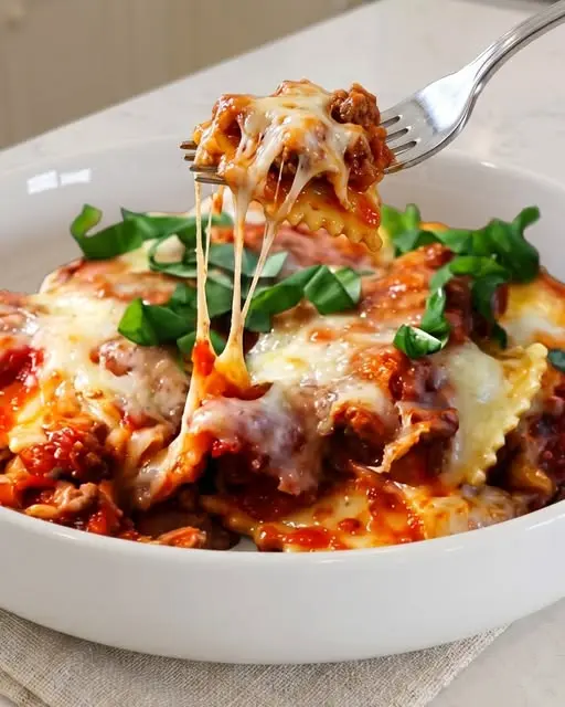 Finished baked ravioli lasagna served in a white dish with a side of garlic bread