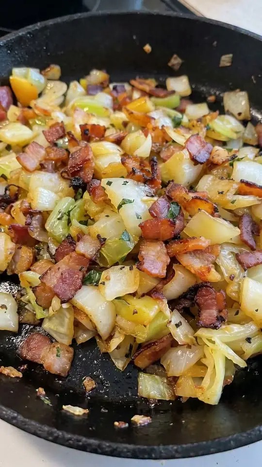 Plated crispy breakfast potato hash with a fried egg on top and fresh herbs