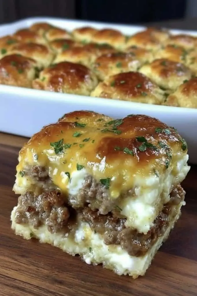 Sliced squares of sausage cream cheese casserole served on a white plate showing the creamy meat filling.