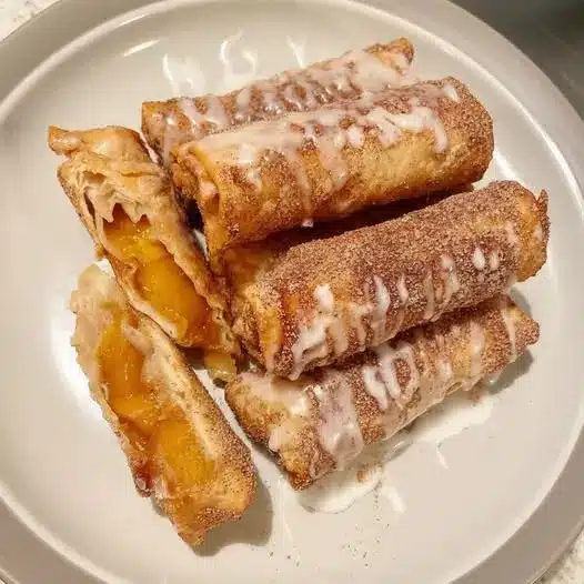 A pan of baked apple cinnamon rolls drizzled with vanilla glaze