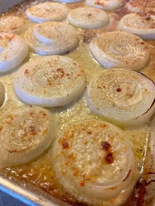 Serving a spoonful of creamy roasted onions from a baking dish