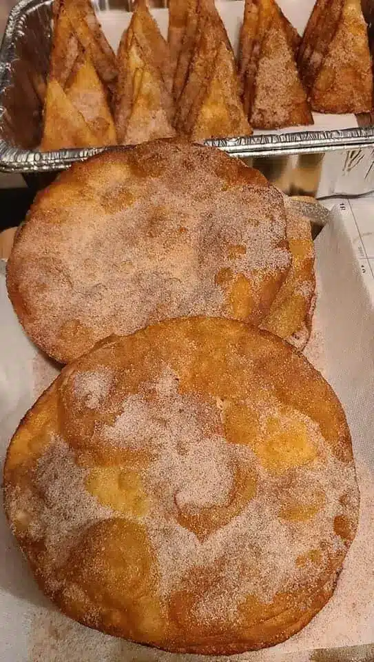 Individual crispy buñuelos displayed with a dusting of cinnamon sugar and a cup of Mexican coffee.