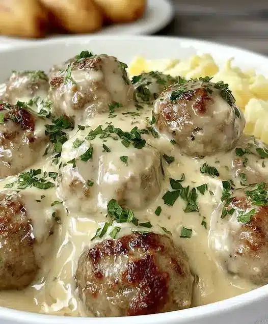 Finished Swedish meatballs served over mashed potatoes with a side of lingonberry jam
