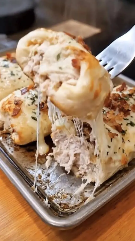 A platter of bacon chicken alfredo breadstick bombs with one pulled apart to show the creamy filling.