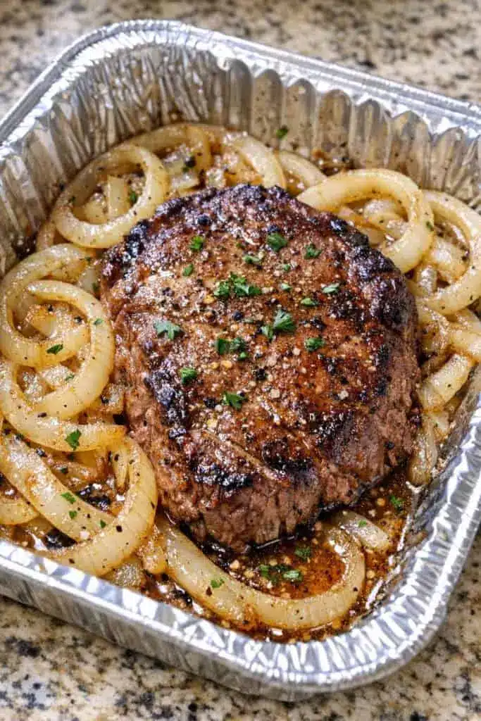 Opened foil packet showing cooked beef patty with melted onions and tender potatoes