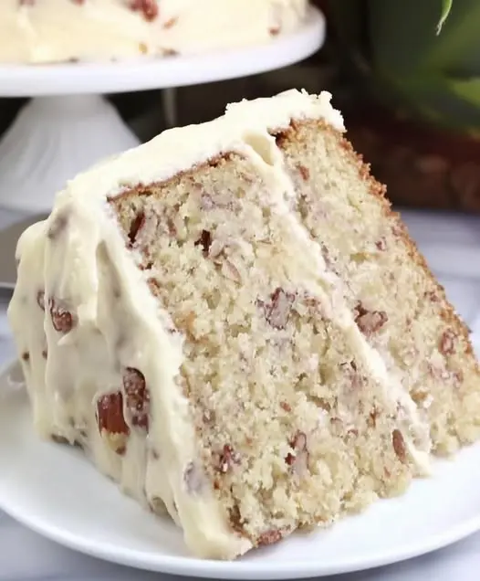 A beautiful sliced butter pecan layer cake with rich frosting and pecan garnishes