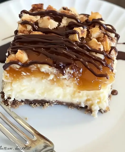 A slice of caramel chocolate cheesecake on a plate, showing the layers of crust, chocolate filling, and caramel topping.
