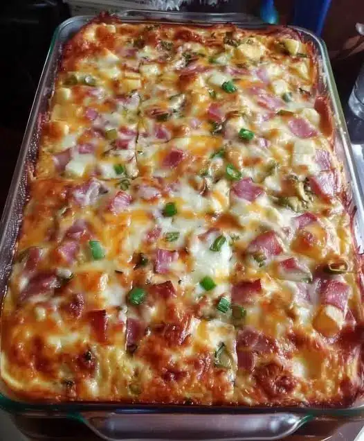 A serving of cheesy ham casserole on a white plate, showing the creamy texture and golden topping.