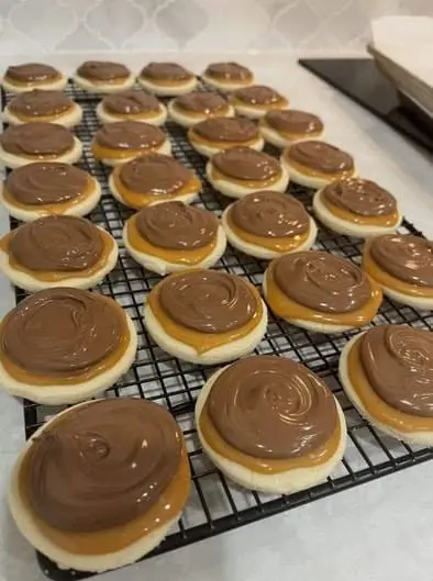 A stack of chocolate frosted cookies with colorful sprinkles on a white plate.