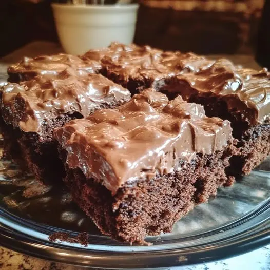 a square of chocolate sheet cake served on a plate with a scoop of vanilla ice cream