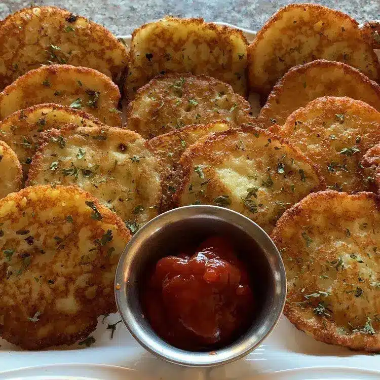 Crispy golden brown potato pancakes served on a plate with a side of sour cream