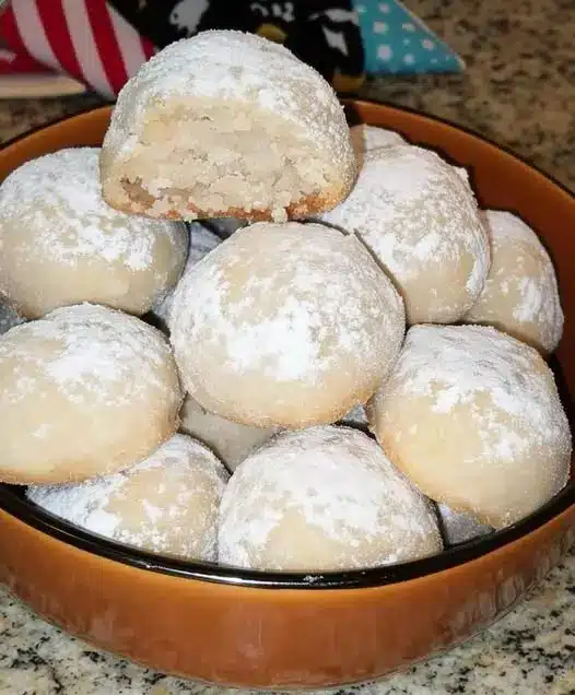 Snowball cookies stacked neatly on a white plate with a festive background