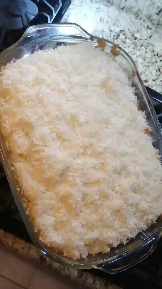 A slice of coconut sheet cake on a white plate showing the tender crumb and thick frosting