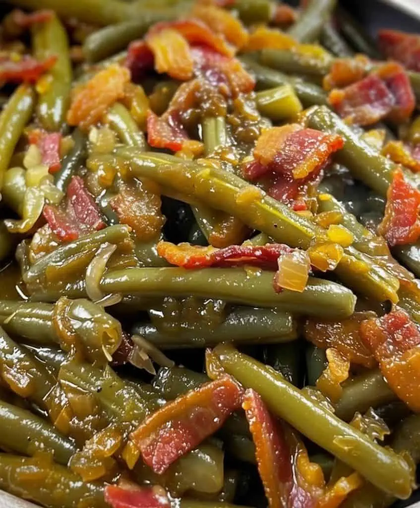 The finished crack green beans in a serving dish, glistening with glaze and topped with crispy bacon bits