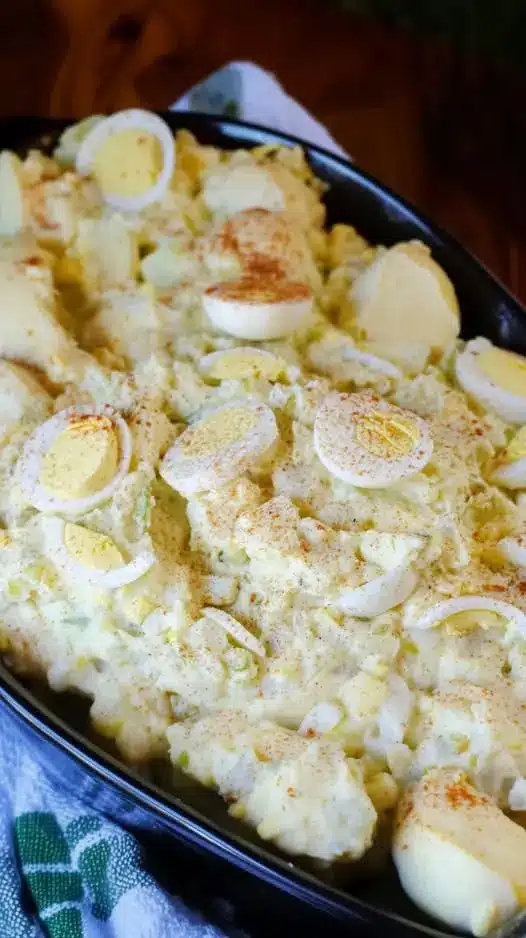 A close up shot of deviled egg potato salad with visible chunks of egg and celery