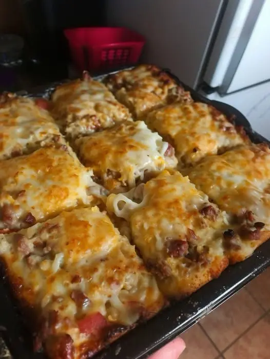 A close-up of a plated chicken enchilada topped with sour cream and avocado
