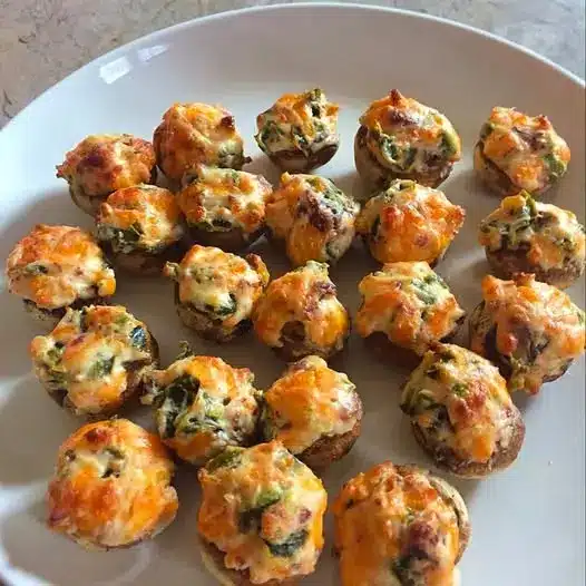 A platter of golden brown baked stuffed mushrooms garnished with fresh parsley