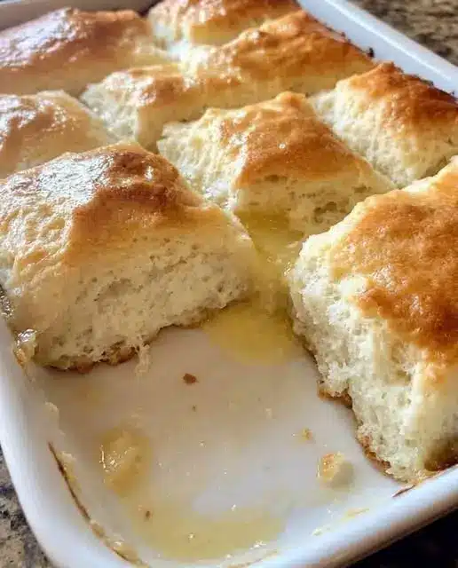 Warm fluffy biscuits served with butter and honey on a white plate