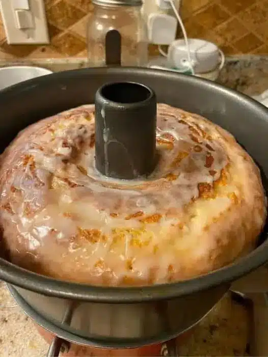A slice of glazed pound cake on a plate with a fork, showing the dense and moist interior crumb.
