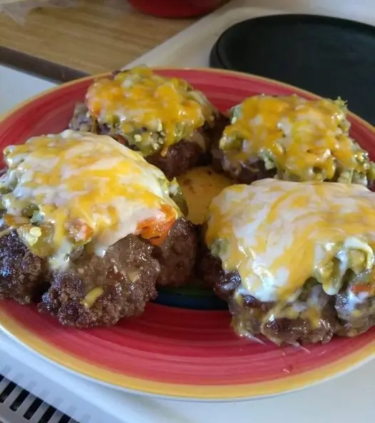 A close-up of a green chile cheeseburger showing the melted cheese and chopped green chiles.