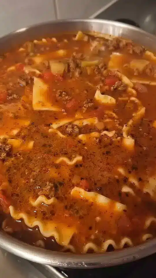 A full pot of beef vegetable soup with a ladle resting inside