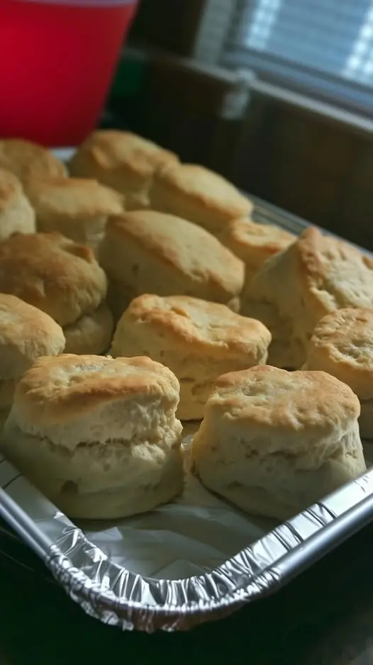A stack of freshly baked buttermilk biscuits with a pat of melting butter on top
