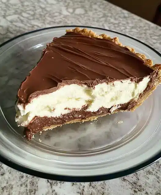 A whole chocolate cream pie with decorative whipped cream swirls and chocolate shavings