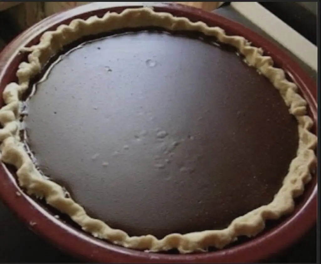 A whole chocolate pie topped with swirls of whipped cream.