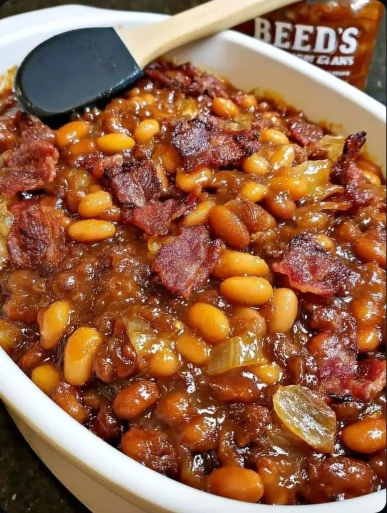 A bowl of cowboy beans served with a side of golden cornbread.