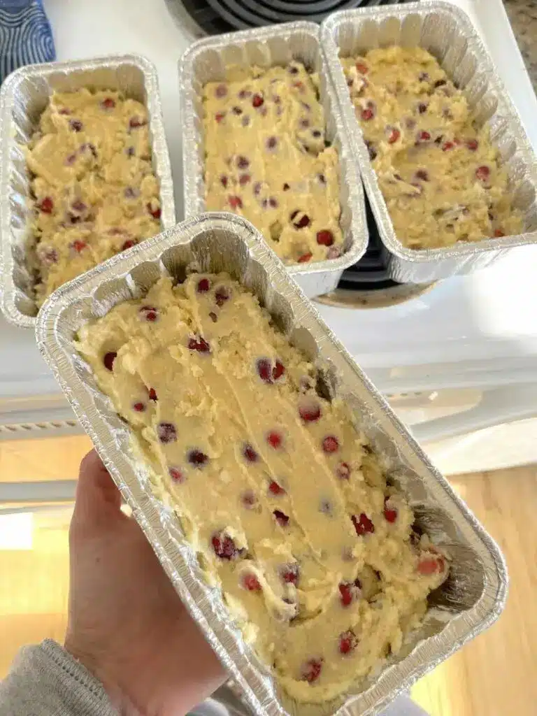 A sliced homemade cranberry loaf served on a wooden board
