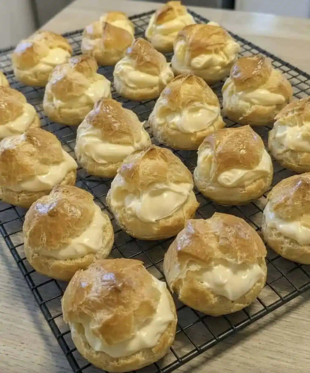A plate of cream puffs dusted with powdered sugar and drizzled with chocolate