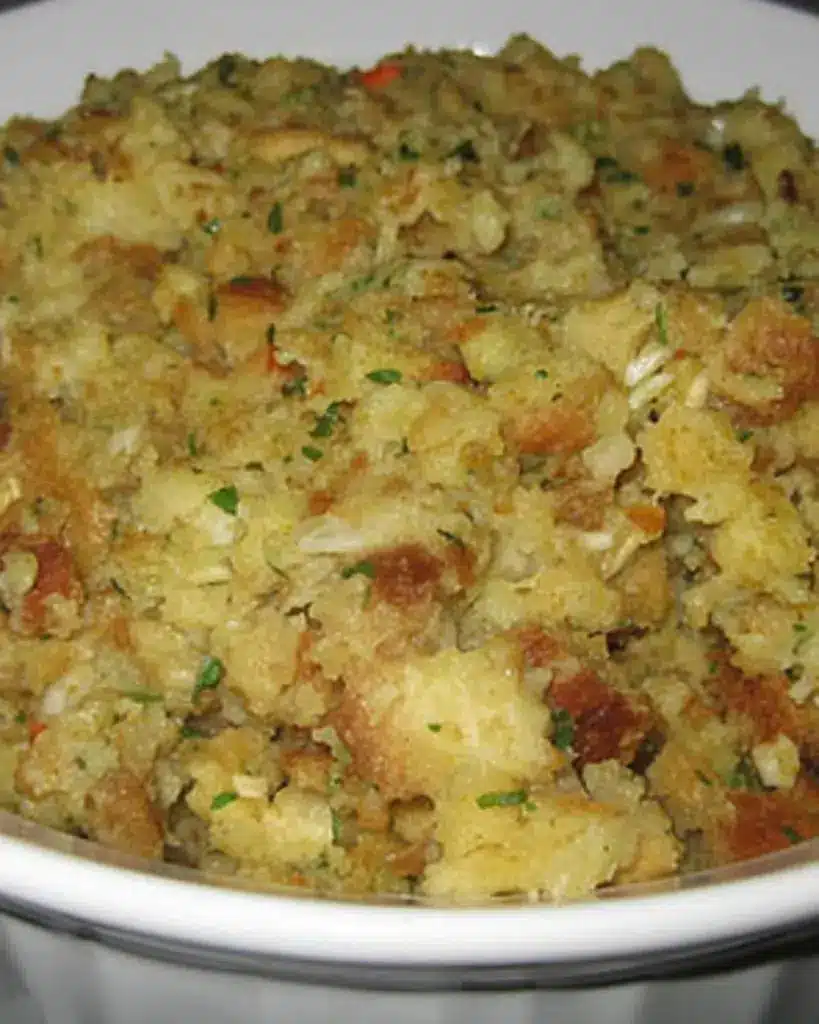 A serving spoon lifting a portion of herb thanksgiving stuffing showing the moist interior and crispy top