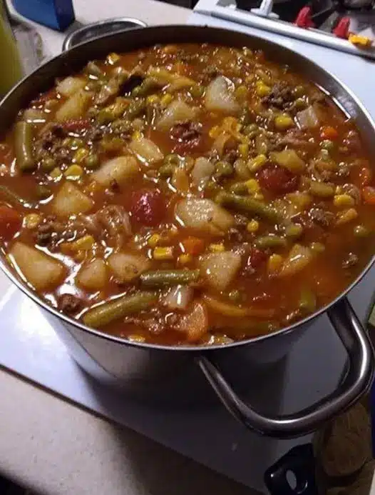 A bowl of vegetable soup served with a slice of crusty bread on the side