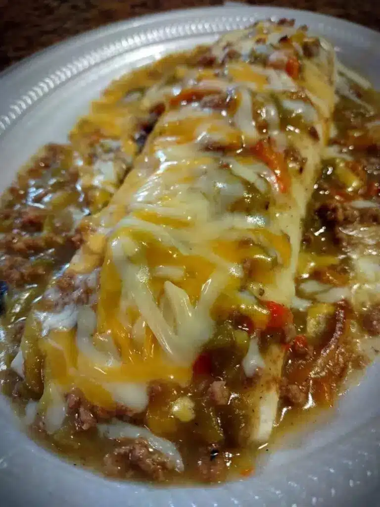 A close-up of a wet burrito cut in half, showing the beef and bean filling inside.