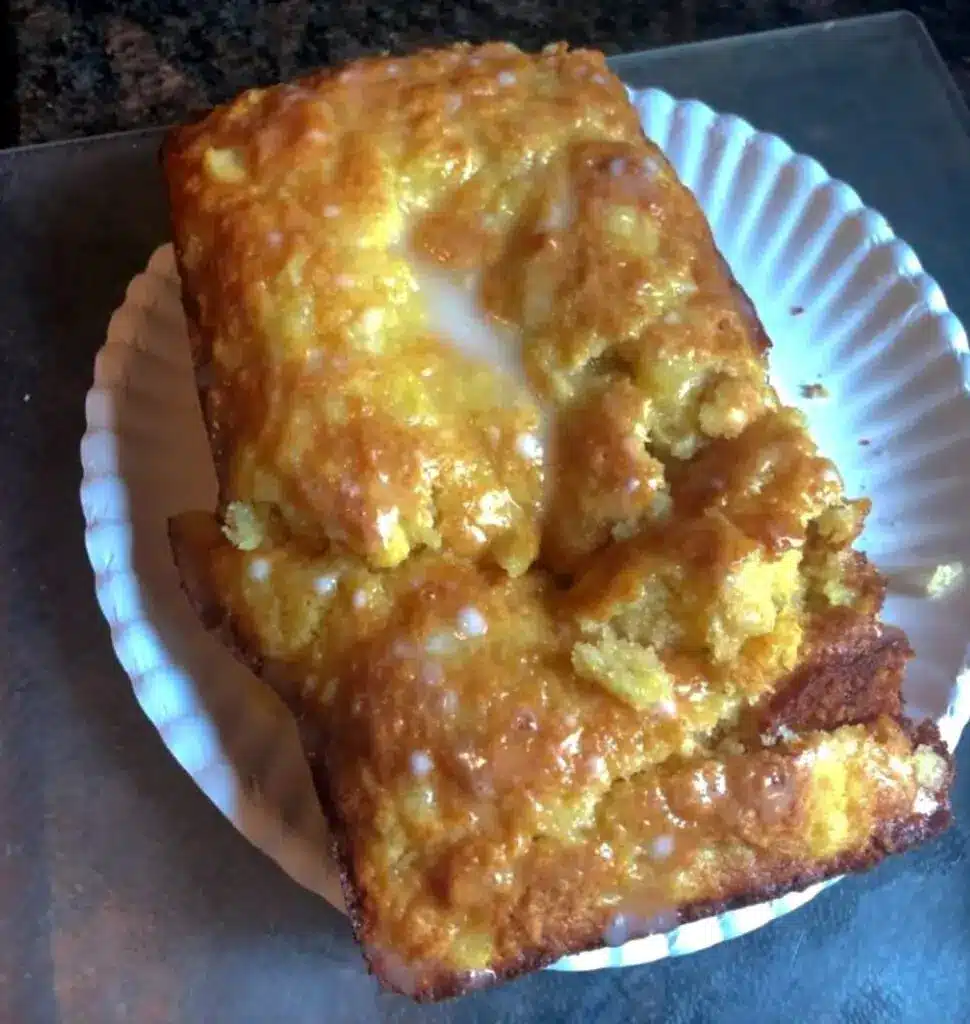 Several slices of moist pineapple bread served on a plate with a dollop of butter.