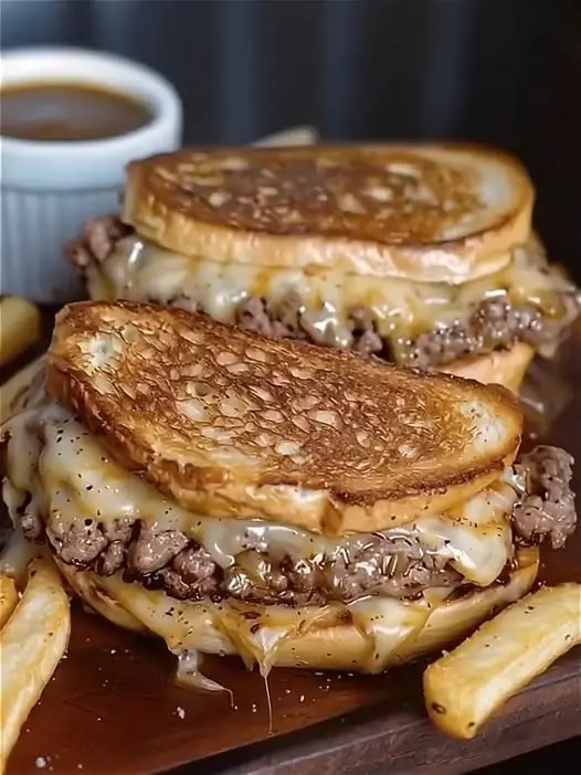 A sliced patty melt showing the layers of melted cheese, beef, and onions.