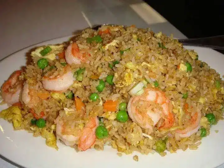 A bowl of shrimp fried rice garnished with fresh green onions and sesame seeds
