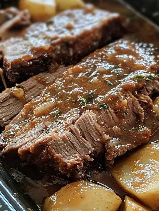 Close up view of sliced beef pot roast served on a plate with gravy.