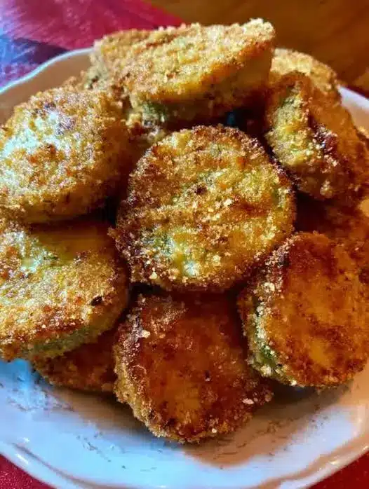 A platter of golden brown southern fried green tomatoes served with a side of creamy dipping sauce