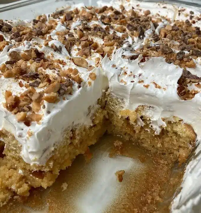 A beautiful slice of toffee butterscotch cake on a white plate with visible toffee bits