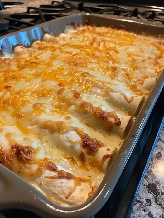 A plate of creamy white chicken enchiladas garnished with cilantro and lime.