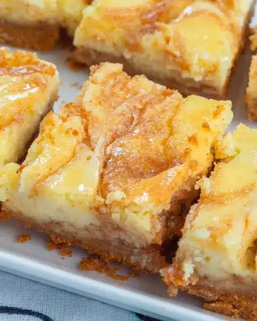sliced cinnamon roll cheesecake bars with a white glaze drizzle