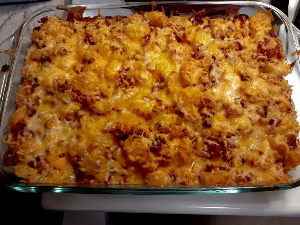 A close up shot of a portion of chicken bacon ranch tot casserole garnished with green onions.