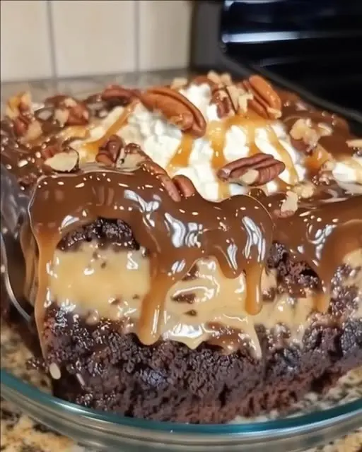 A slice of chocolate caramel poke cake on a plate showing the caramel-filled holes inside the sponge.