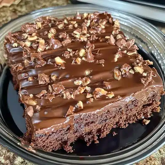 A close-up shot of a sliced chocolate pecan sheet cake showing the moist crumb and thick pecan frosting.