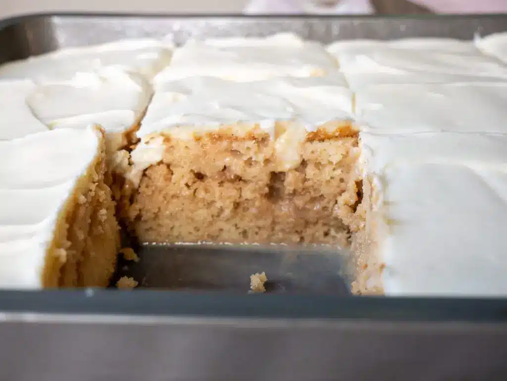 A slice of cinnamon roll poke cake showing the internal cinnamon filling layers.