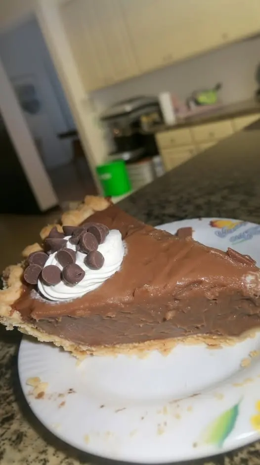 The finished chocolate cream pie topped with clouds of whipped cream and chocolate shavings.