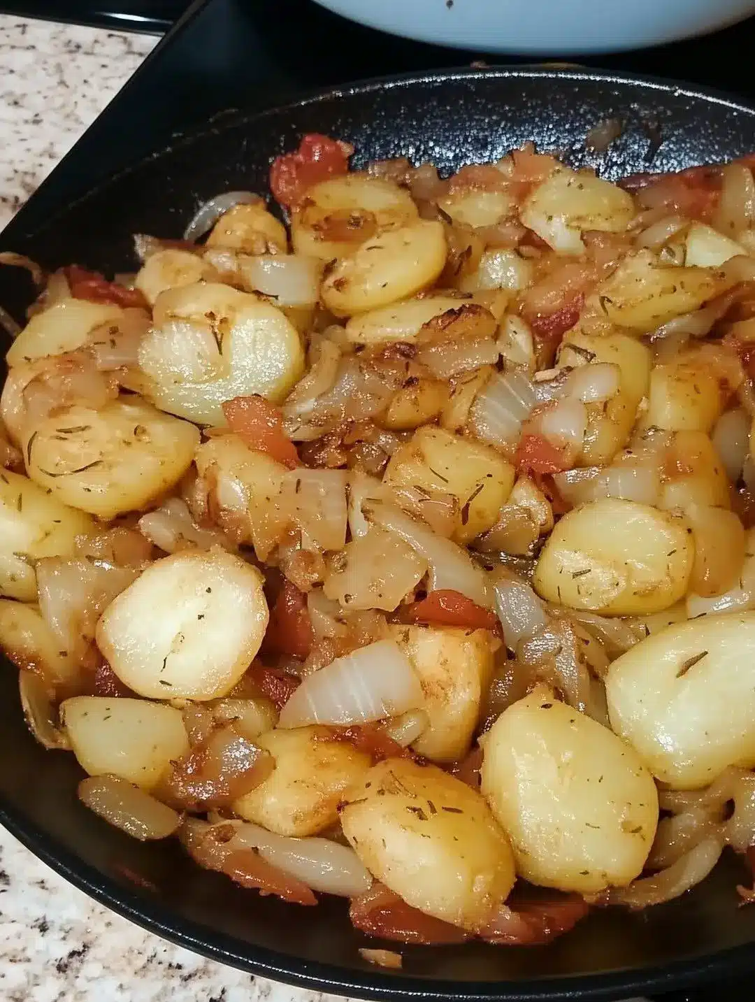 Fried potatoes and onions served on a plate with fresh parsley garnish