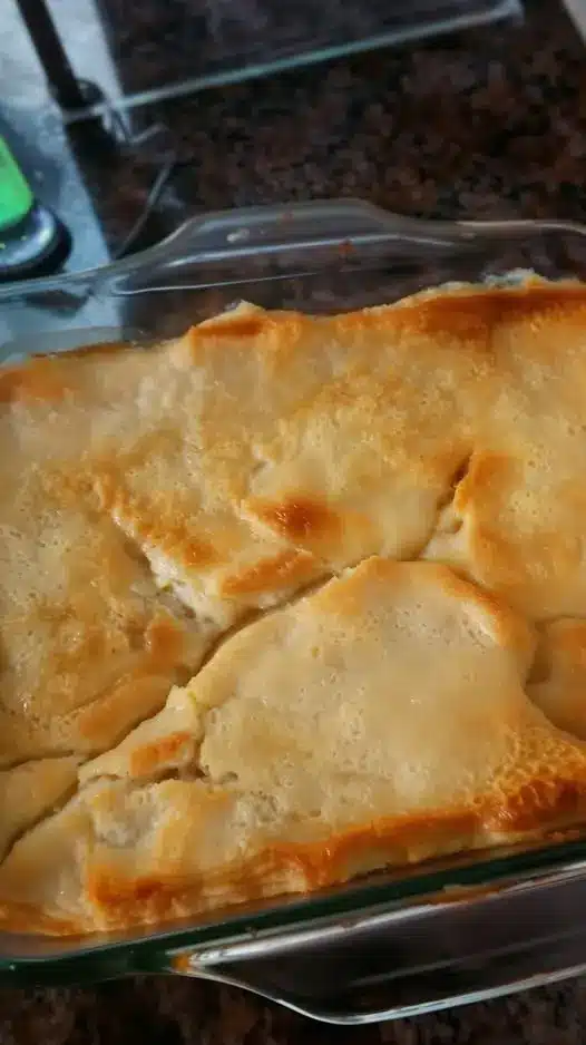 A close up shot of a slice of chicken pot pie on a white plate showing the thick gravy and vegetables.